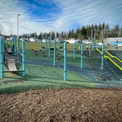 Light blue, black and green playground on pour in place (PIP) rubber surfacing and dinoflex rubber tiles