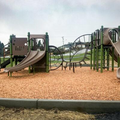 brown and green playground on engineered wood fibre (EWF) surfacing