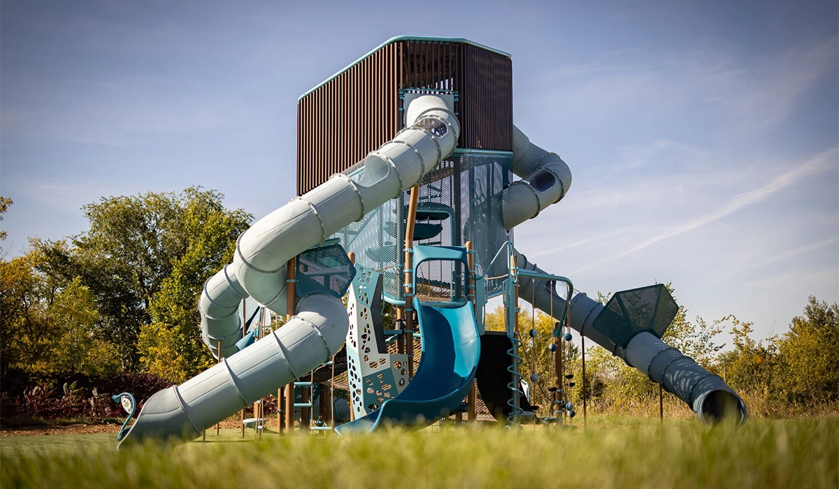 A tall blue and brown playground tower with three long slides