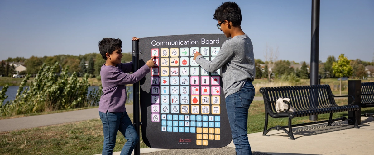 Two boys pointing at a Symbol Communication Board